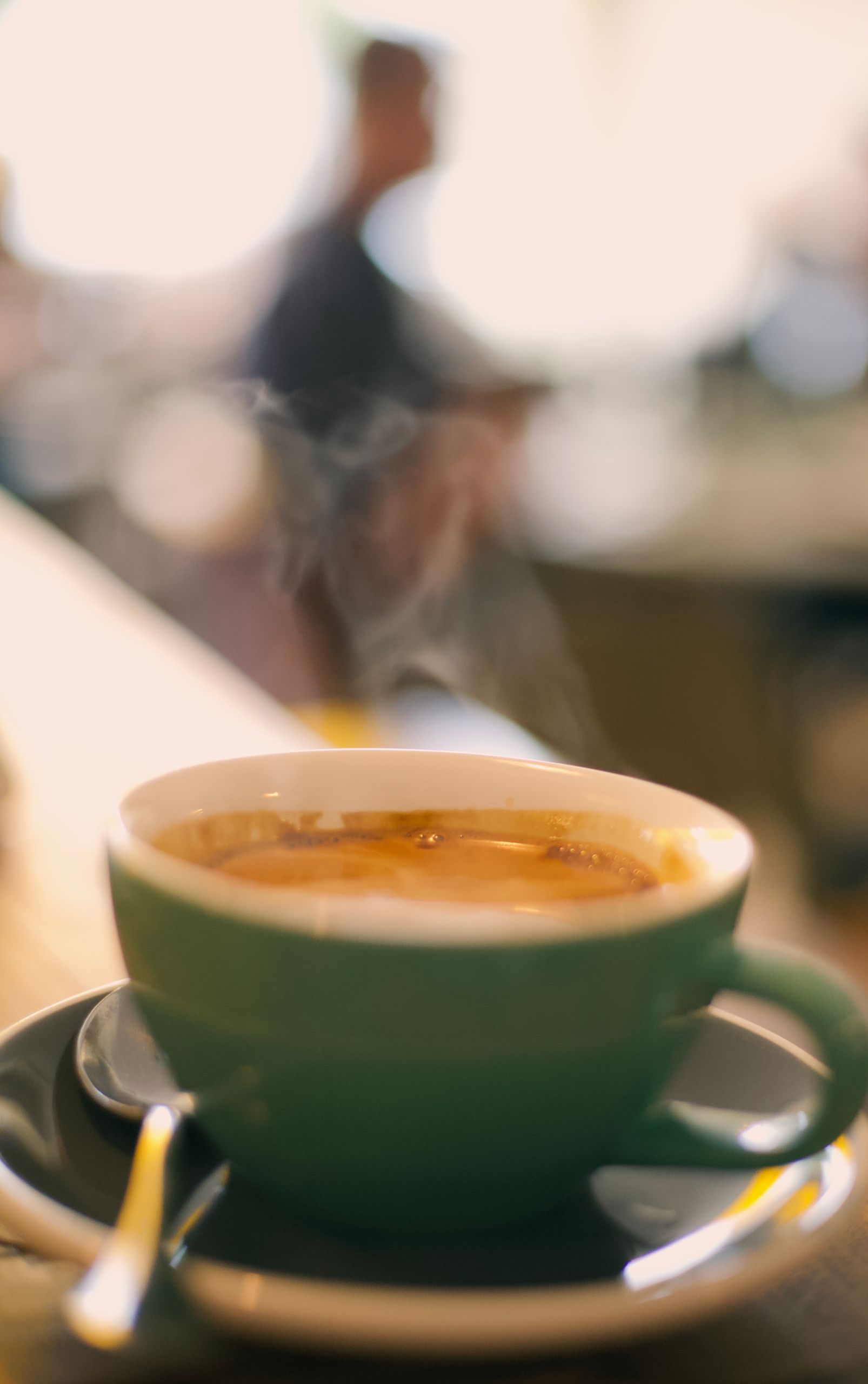 A steaming coffee cup on a table with a blurred cafe background, capturing a warm ambiance.